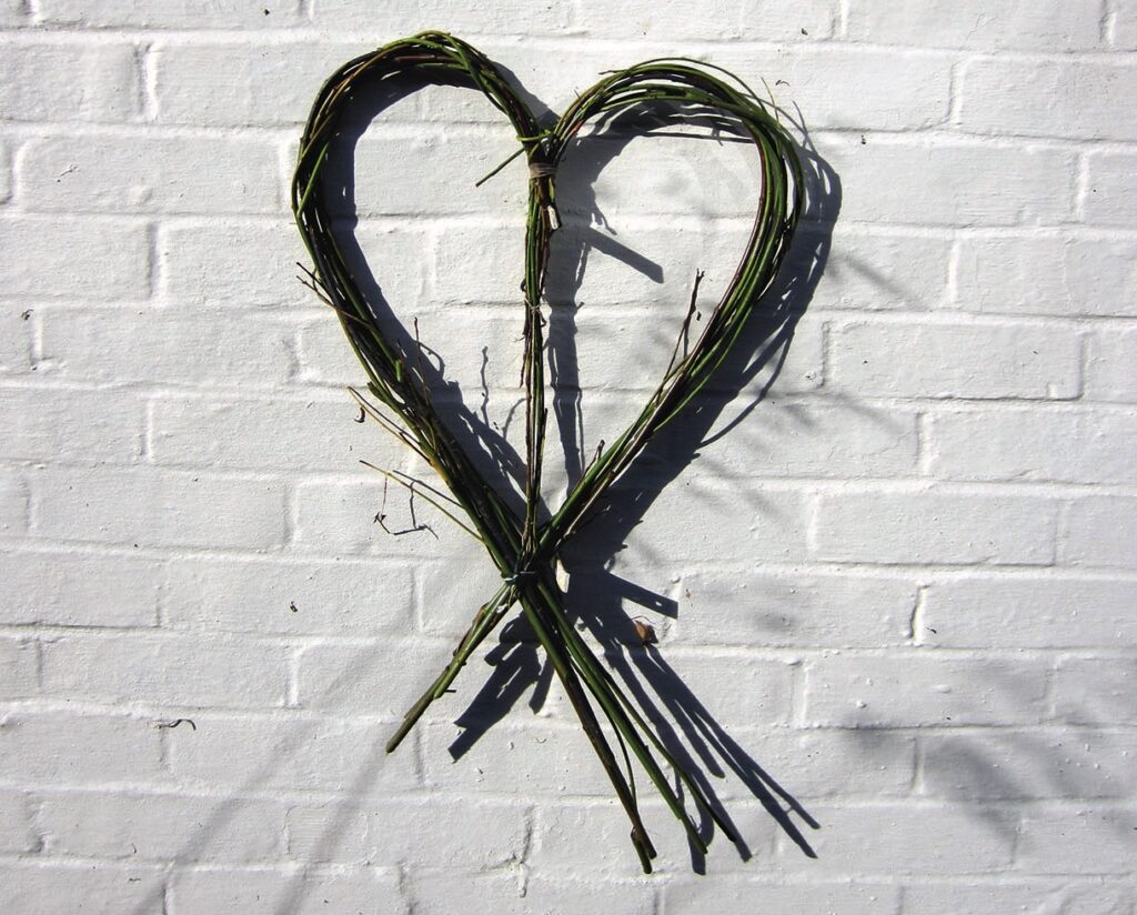 Heart-shaped stick sculpture on white brick wall.
