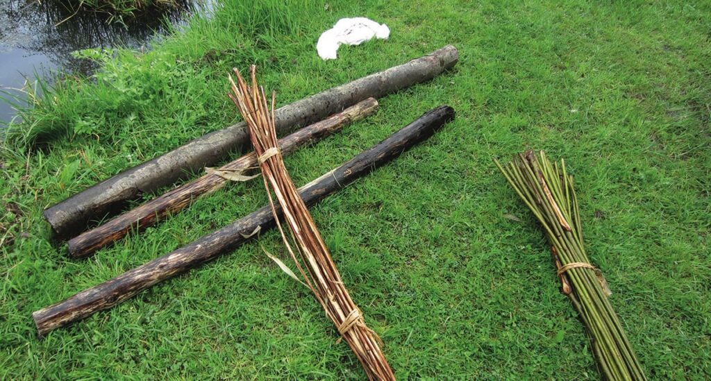 Logs and bundles of sticks on grass