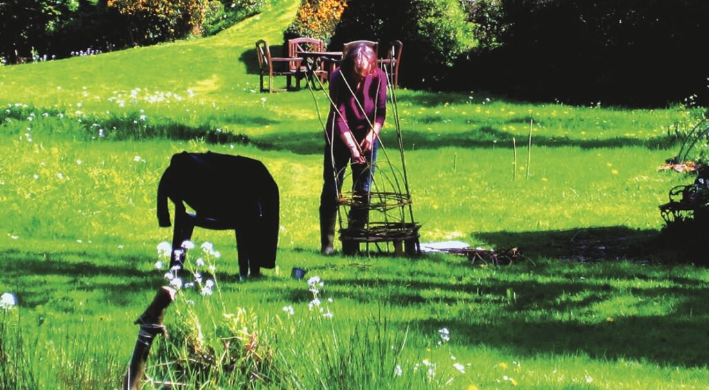Person weaving garden structure outdoors