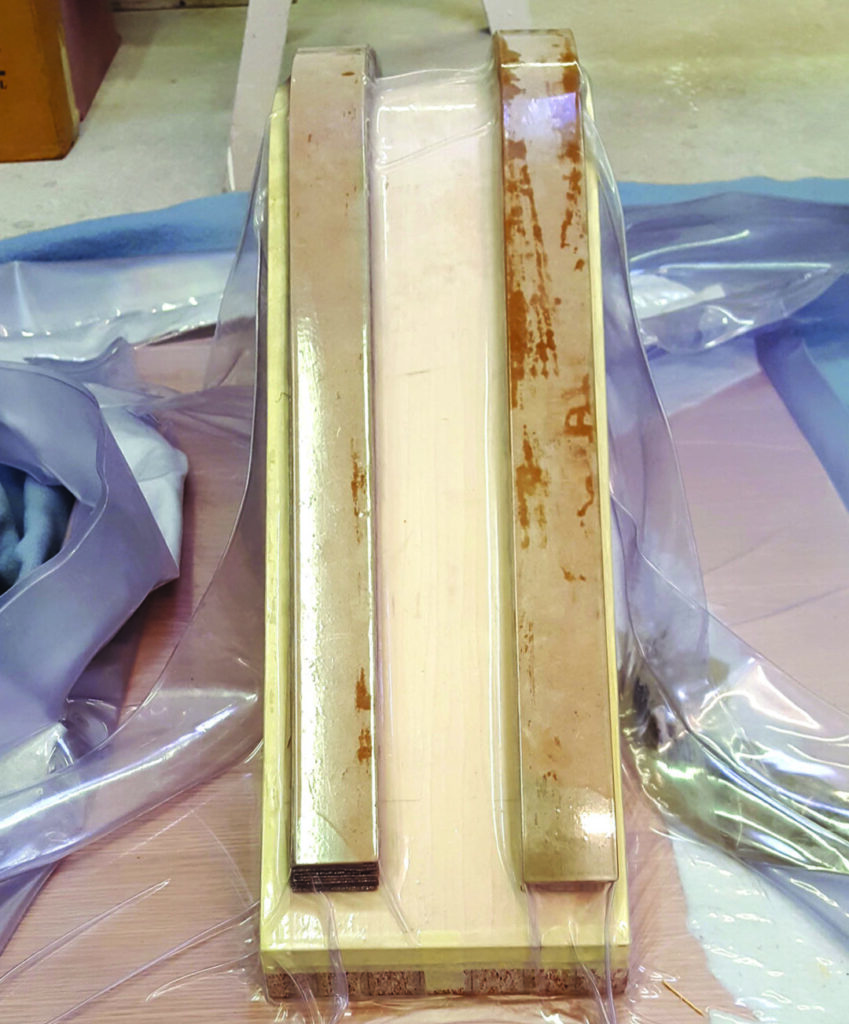 Vacuum bagging a foam surfboard blank in workshop.