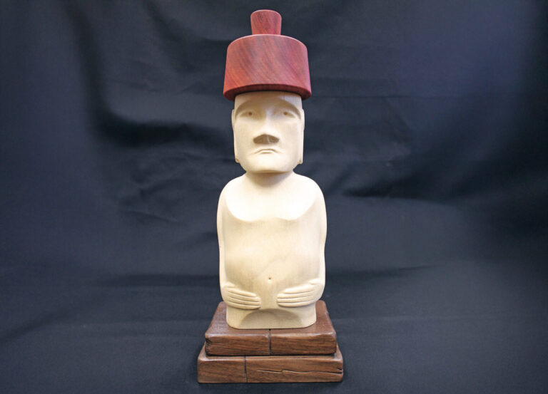 Wooden statue with red hat on dark background.