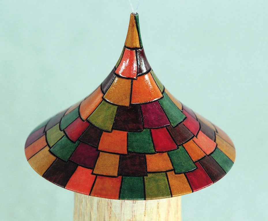 Colourful mosaic-tiled conical roof sculpture.