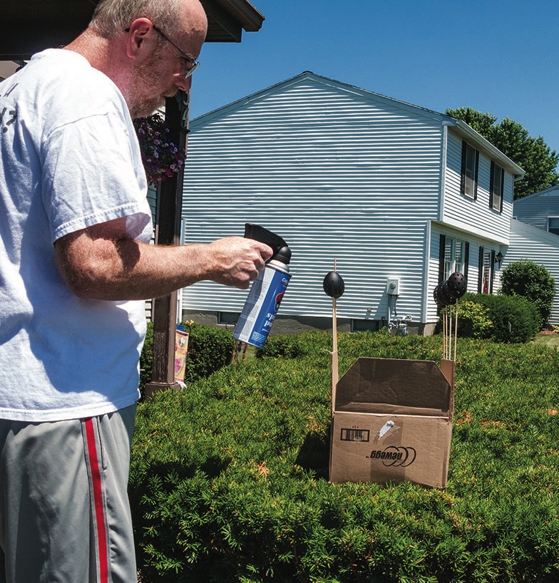 Man uses spray paint on outdoor setup.