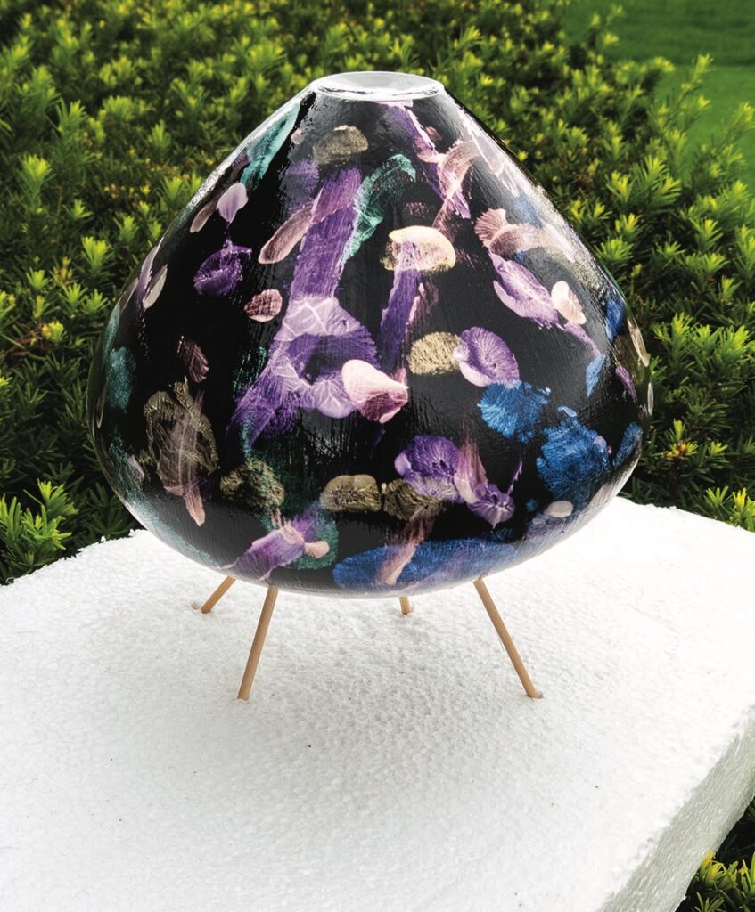 Colourful abstract globe sculpture on wooden tripod