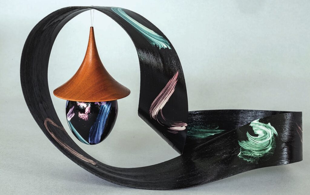 Abstract wooden sculpture with vibrant brushstrokes on black.