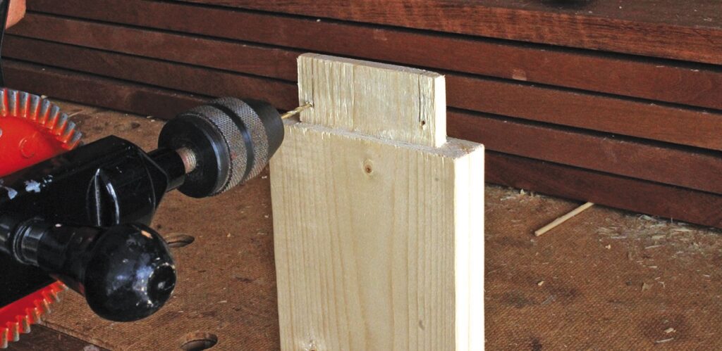 Hand drill creating dowel hole in wood block