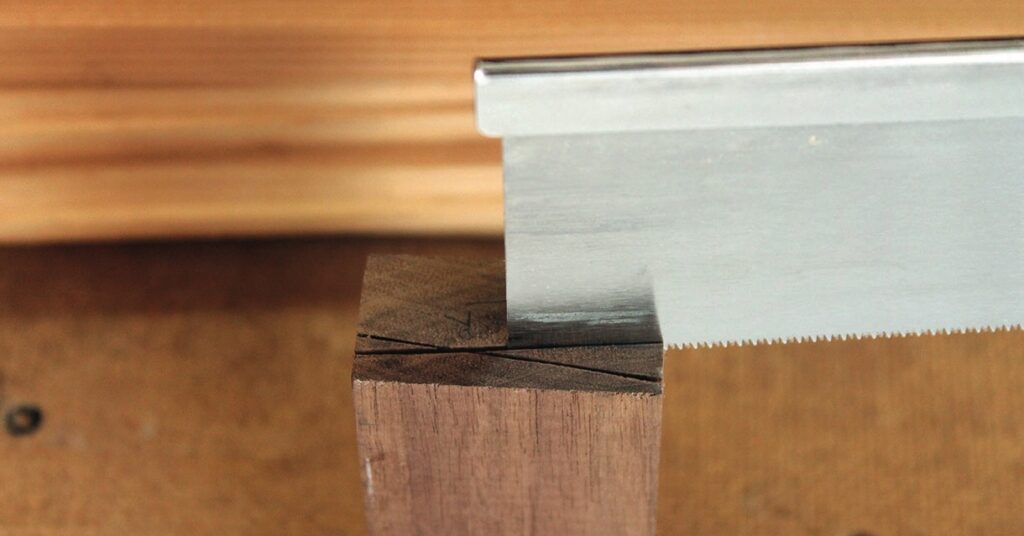 Saw cutting wooden block at marked line.