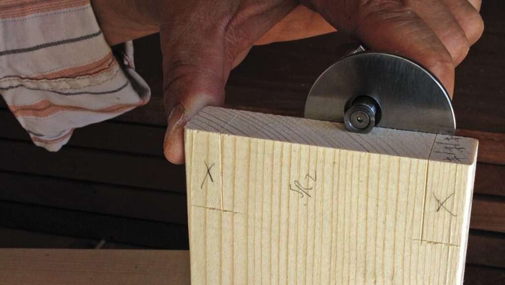 Hand using marking gauge on wood