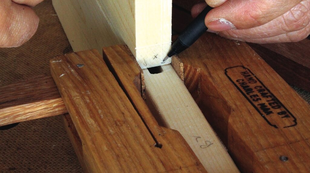 Woodworker marking dovetail joint on a wooden piece.