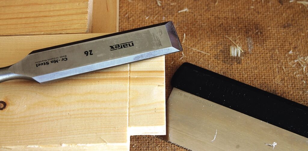 Woodworking tools: chisel and saw on wood blocks.