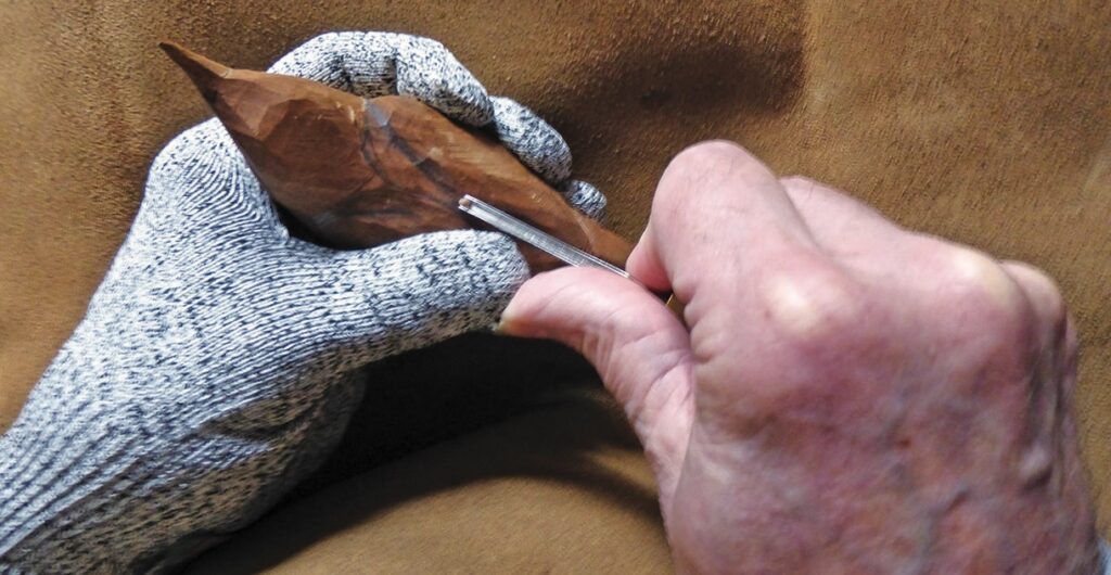 Hand carving wood with a chisel.