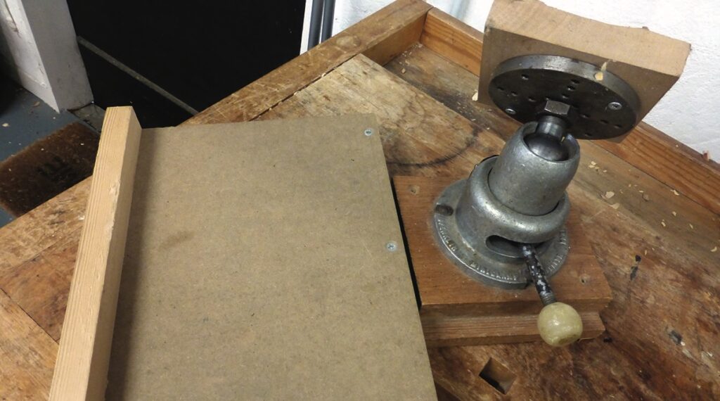 Mechanical vice tool on wooden workbench.