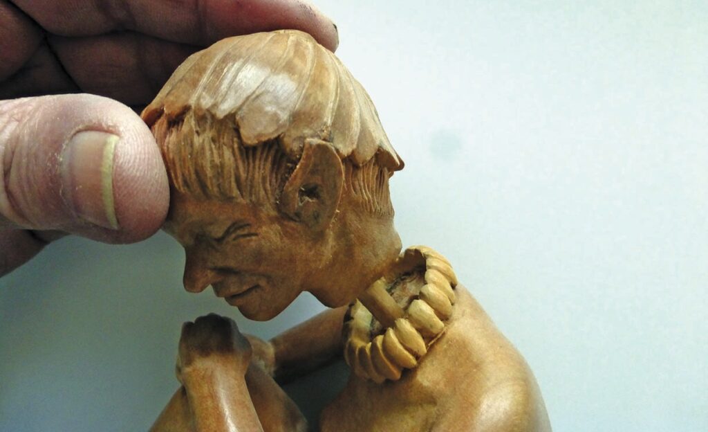 Hand holding intricately carved wooden figure