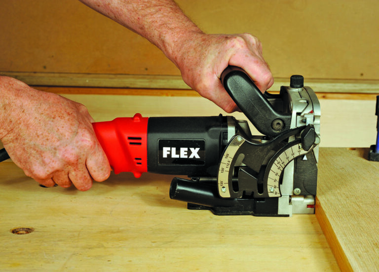 Person using electric wood biscuit joiner tool.