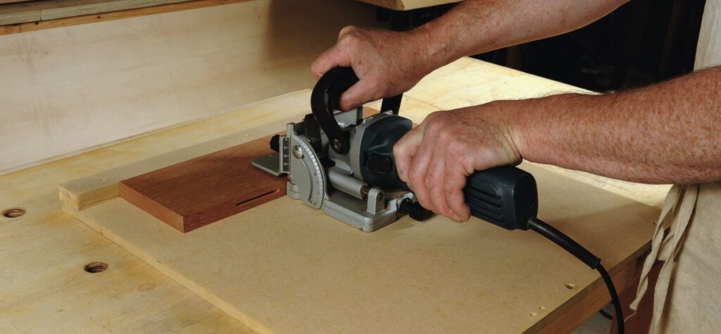 Person using a biscuit joiner on wood.