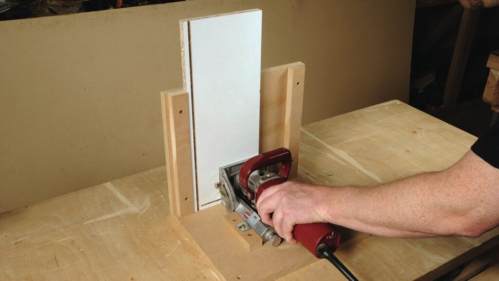 Person using joinery tool on wooden board.