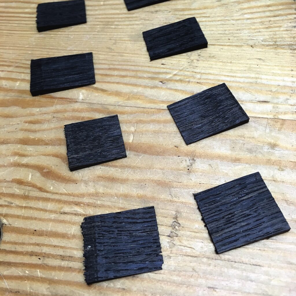 Black wood squares on wooden table surface.