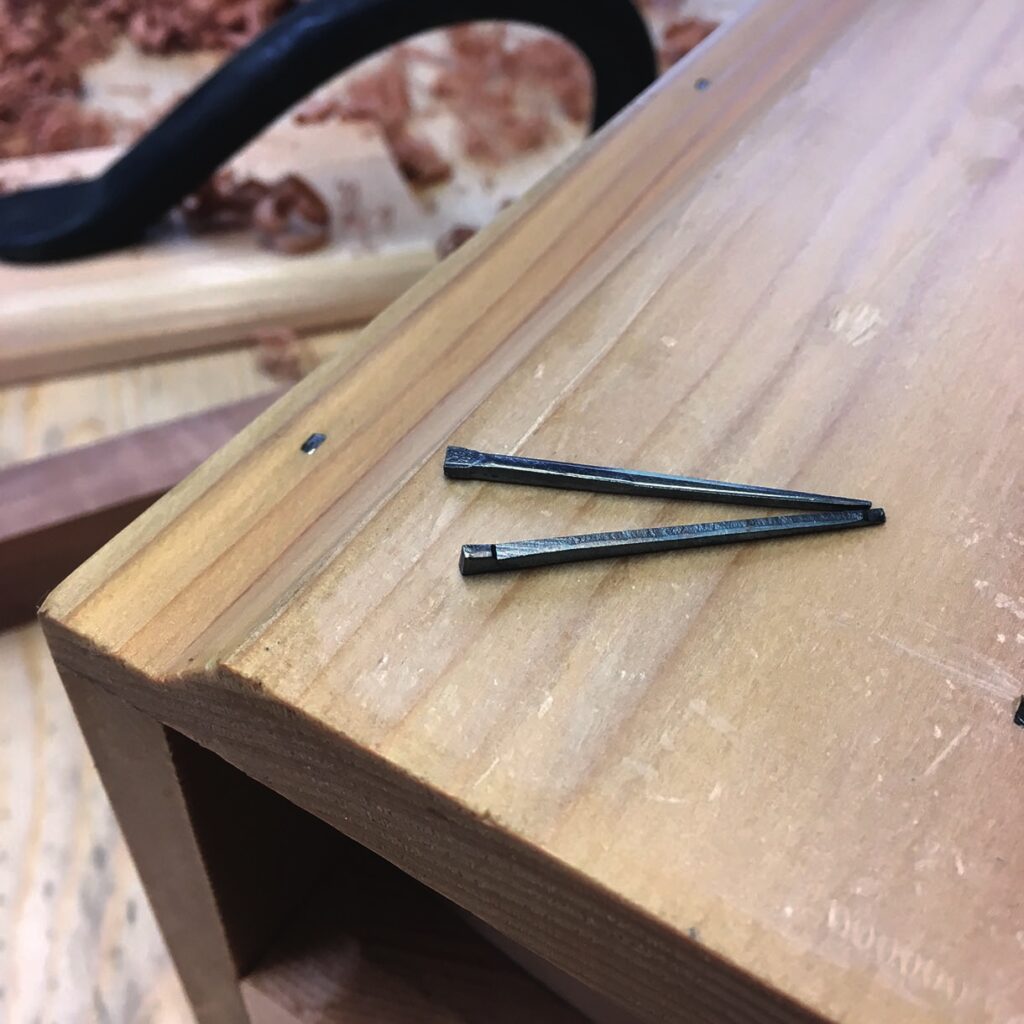 Woodworking setup with nails on wooden surface.
