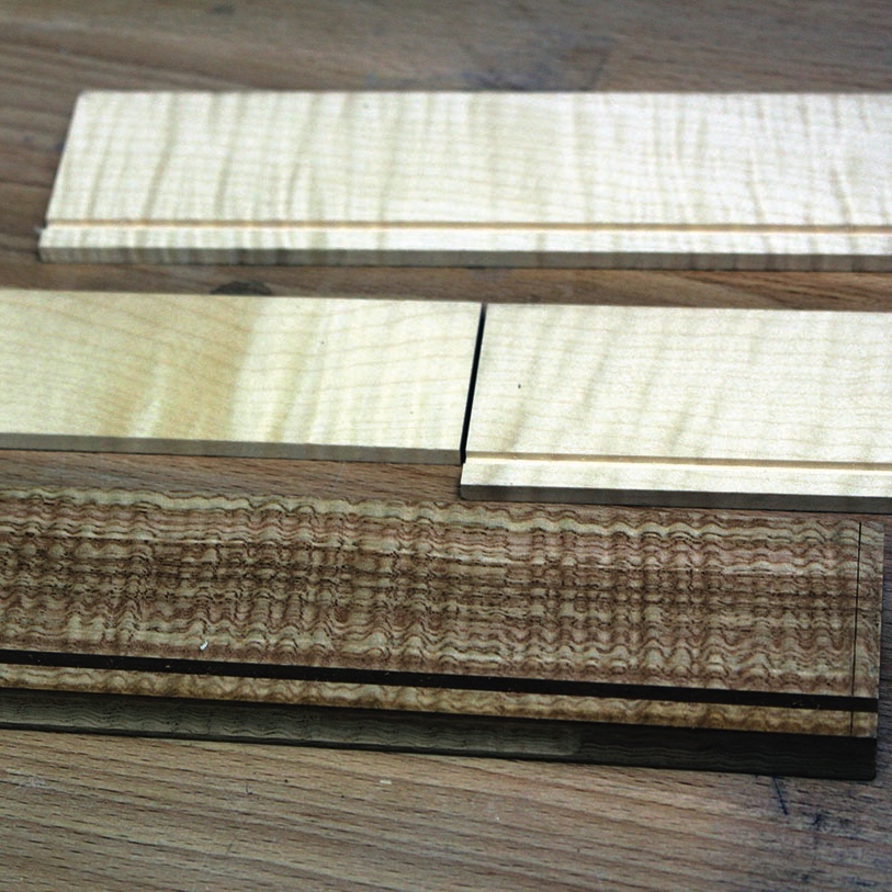 Maple and walnut wood veneer samples on table.