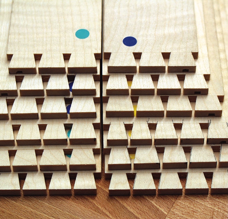 Close-up of wooden dovetail joints with coloured dots.