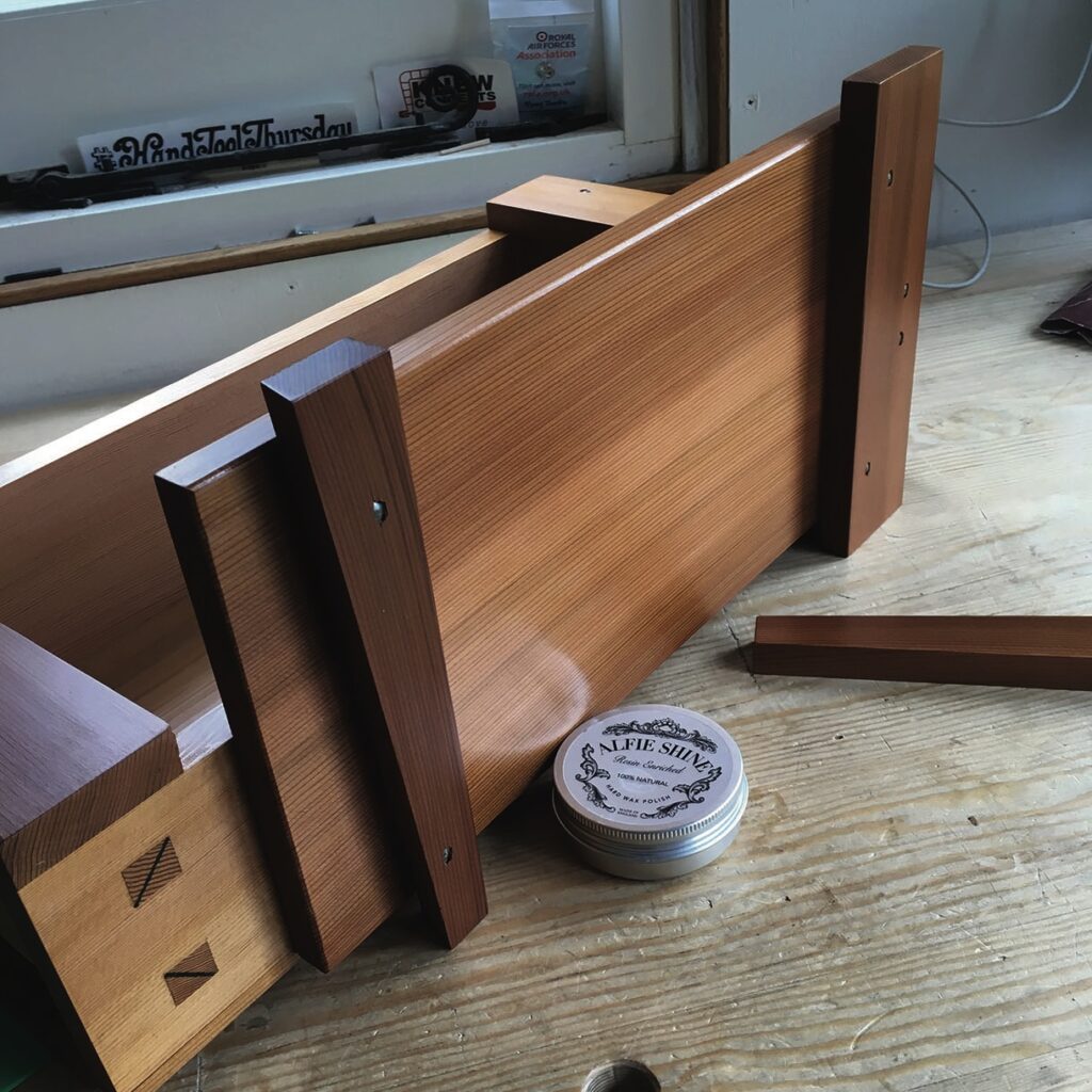 Wooden drawer assembly on workbench with wax polish.