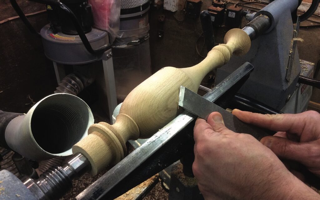 Woodturning spindle on lathe in workshop.