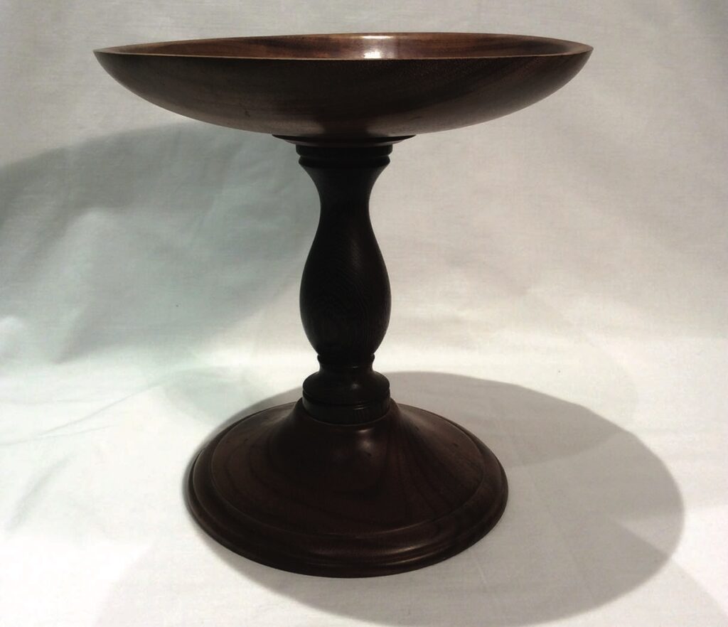 Elegant dark wood pedestal bowl on display.