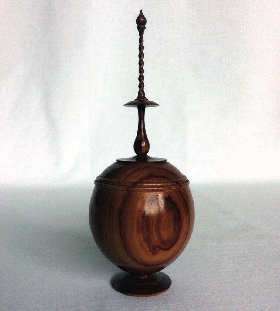 Wooden decorative jar with intricate lid design.