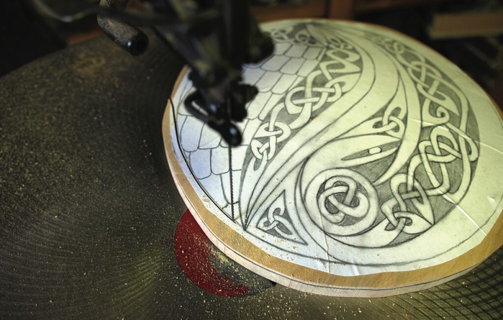 Scroll saw cutting intricate Celtic wood design.