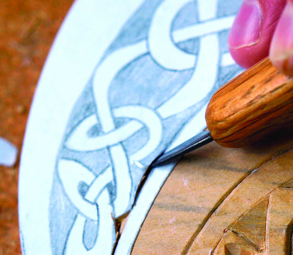 Celtic knot carving in progress with hand tools.