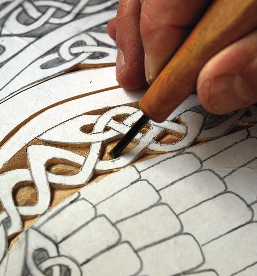 Hand carving intricate Celtic knot pattern on wood