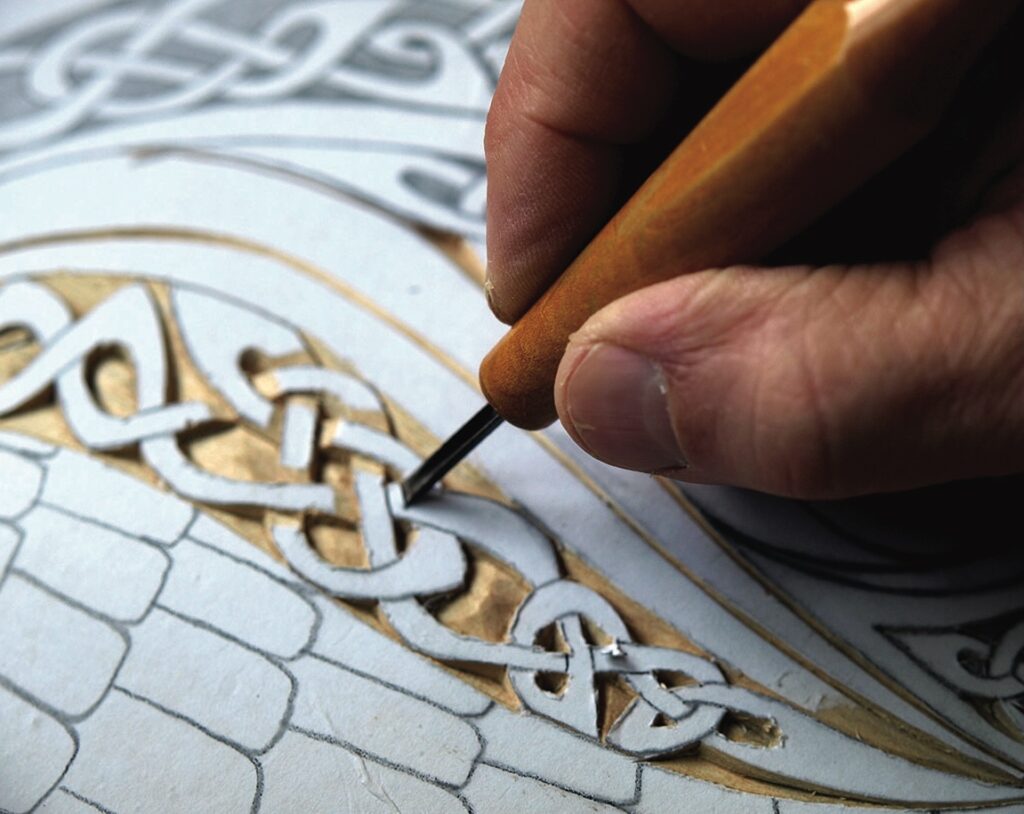 Hand carving intricate wooden pattern.