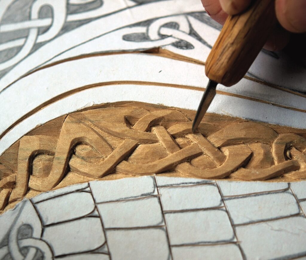 Woodworker carving intricate Celtic knot pattern
