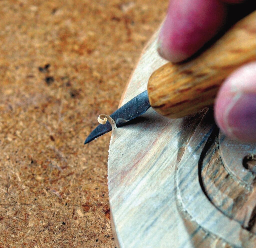 Wood carving with a chisel tool.