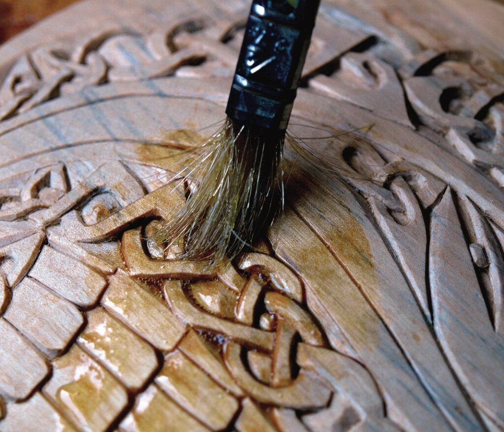 Detail of a brush varnishing wood carving.