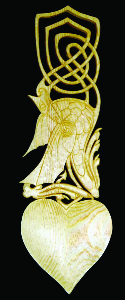 Intricate wooden lovespoon with heart and bird design.