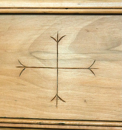 Engraved cross design on wooden surface.