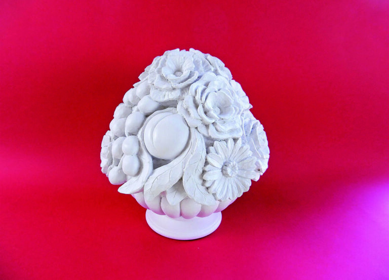 Sculpted floral arrangement on vibrant red background.