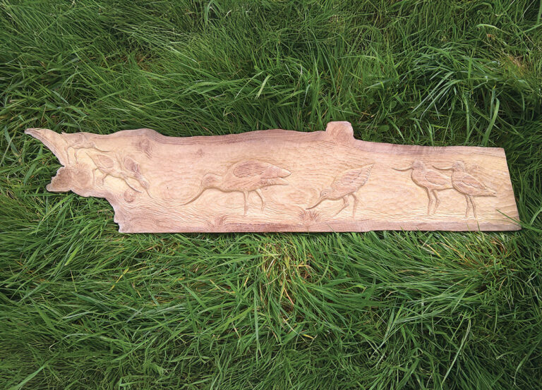 Wooden carving of birds on green grass