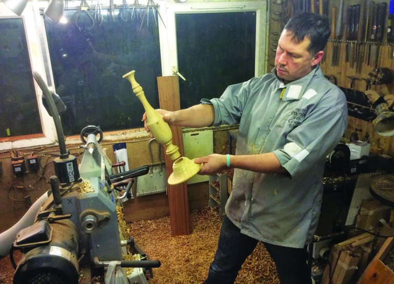 Man crafting wooden object in workshop.