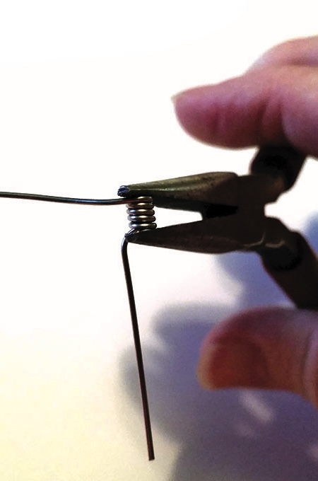 Hand using pliers to bend wire.