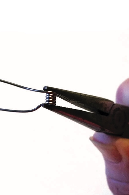 Pliers twisting wire coil tightly.