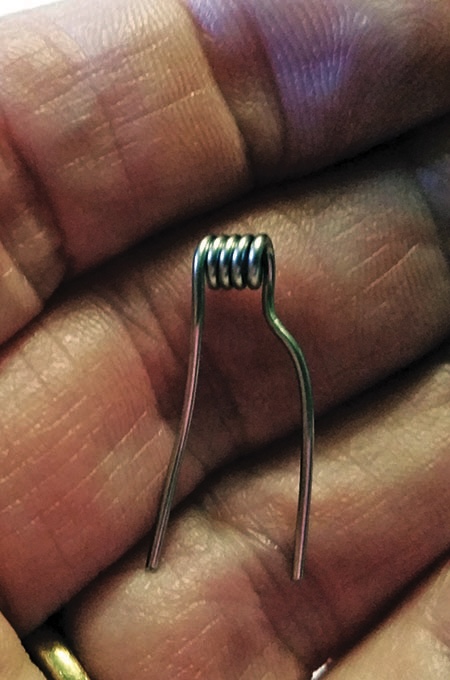 Hand holding a small metal coil.