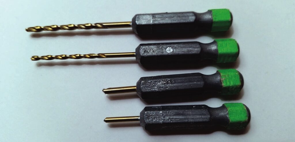 Four black and green small drill bits arranged.