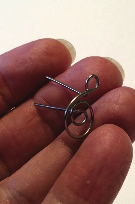 Hand holding small metal wire clip.