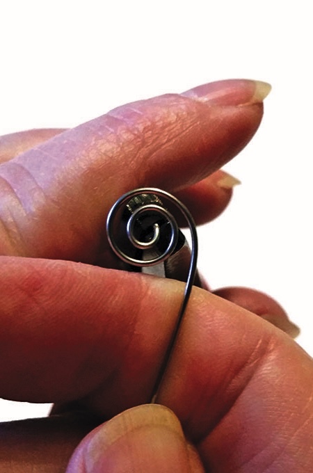 Hand holding a coiled metal wire.