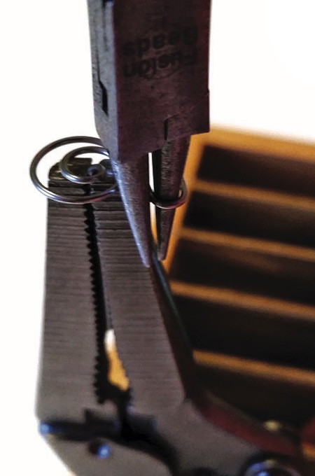 Close-up of pliers holding a metal ring