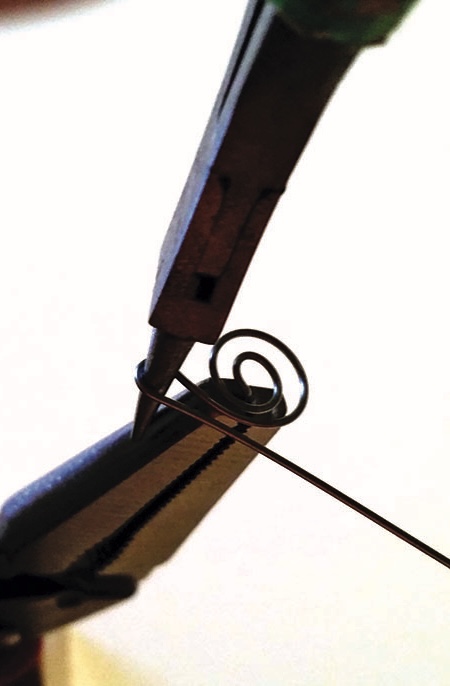 Pliers bending wire into a spiral shape.