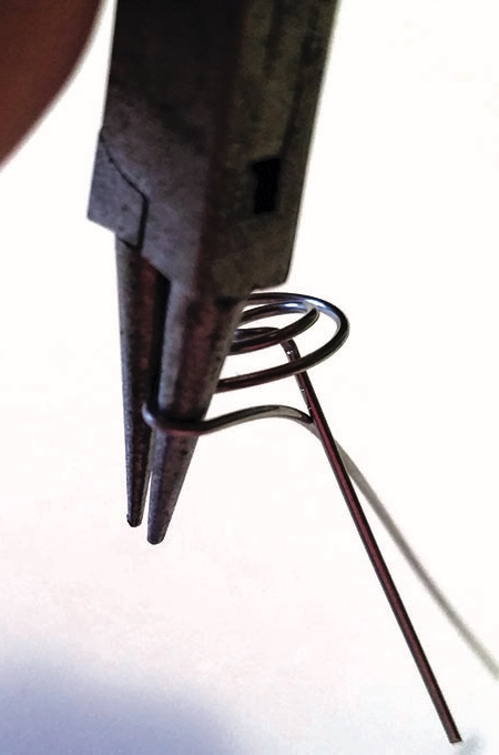 Pliers bending a wire into a spiral shape.
