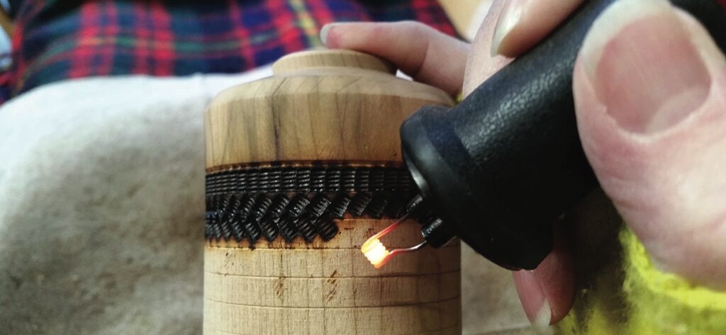 Person burning design into wooden object.
